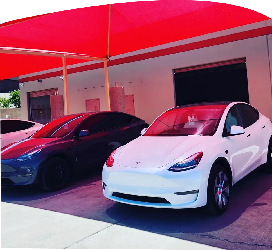 Two tesla model y's parked in front of a garage.